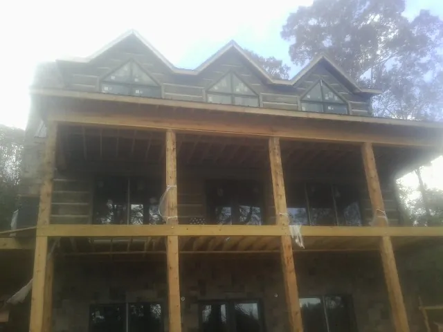 Dormers and porch framing on a large log home under construction — Roof Coating work by our crew in Evans
